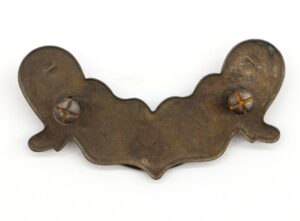 Traditional bail drawer pull in antique brass finish with a curved, scalloped plate and two visible mounting screws.