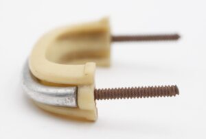 Close-up of a mid century drawer pull with an ivory plastic grip and nickeled brass mount, showing the attached mounting screw.