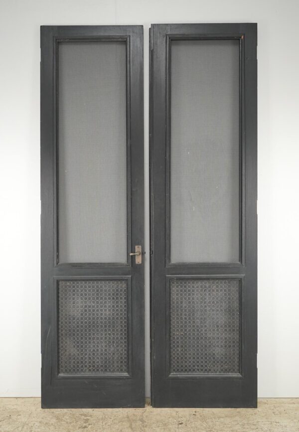 Vintage black wood double screen doors with two mesh panels and original brass hardware attached.