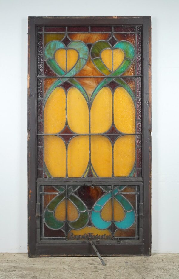 Rectangular leaded stained glass church window with yellow, amber, and blue panels, an opening lower section, and a dark frame.