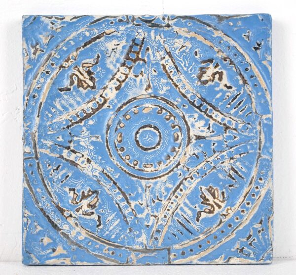 Handcrafted wall panel made from ornate four-fold tin, shown as a square blue and white decorative surface with a raised circular center and arched sections.
