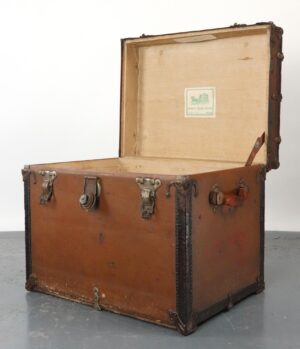 Open brown leather travel trunk with nickel-finish hardware, shown with the lid raised and a Sage's Trunk Depot label inside.