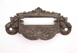Victorian cast iron drawer pull with an ornate apothecary design and a label slot opening.
