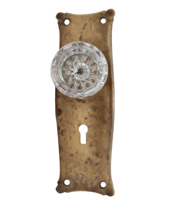 Vintage passage door knob set with a clear round glass knob on an antique brass back plate and keyhole opening.