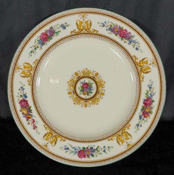 Dinner plate with a multicolored floral and griffin pattern around the rim and center medallion.