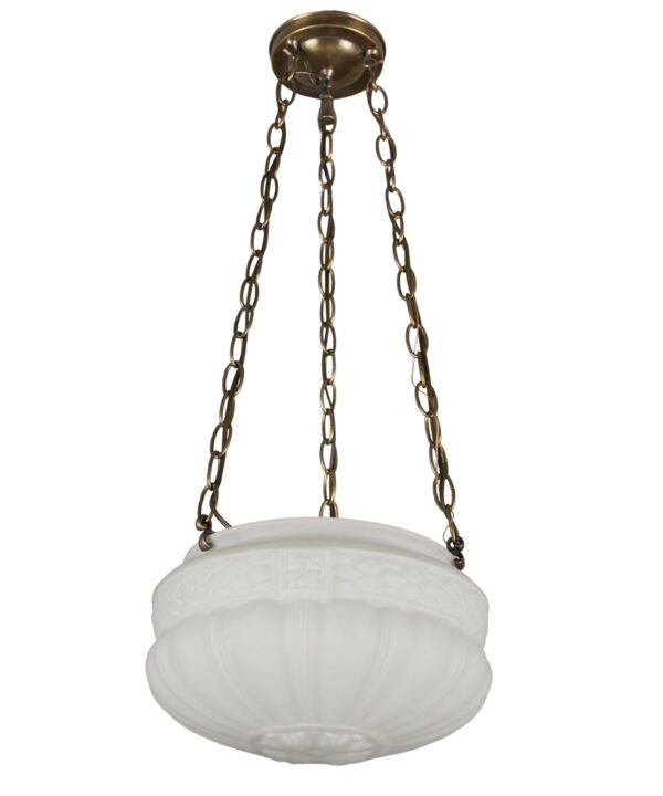 Pendant light with a white fluted glass bowl shade suspended by three chains from an antique brass canopy.