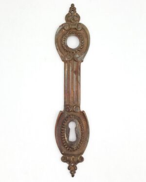 French-style brass door back plate with keyhole, shown full length with ornate scroll detailing and an antique brass finish.
