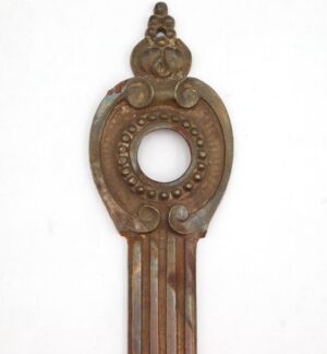 French-style brass door back plate with keyhole, shown vertically with an ornate oval escutcheon and ridged lower stem.