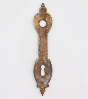 French-style brass door back plate with a keyhole, shown vertically with ornate ends and surface wear.