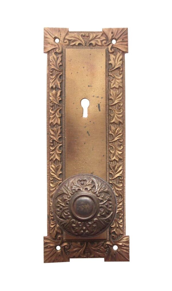 Antique bronze door knob set with an ornate rectangular back plate and round knob, shown in a straight-on view with keyhole cutout and four mounting holes.
