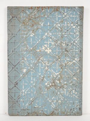 Handcrafted wall panel made from antique tin with a blue diamond cross pattern and worn white and gray details.