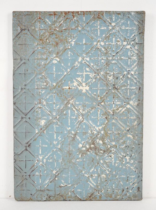 Handcrafted wall panel made from antique tin with a blue diamond cross pattern and worn white and gray details.