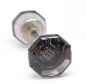 Pair of octagon glass door knobs with visible bubble center detail and metal shanks, shown in close-up with one knob in the foreground and one out of focus behind it.