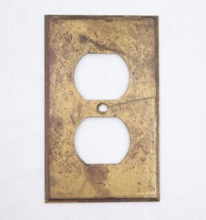 Vintage brass duplex outlet cover plate with a slight beveled edge and surface wear, shown front view with two outlet openings and a center screw hole.