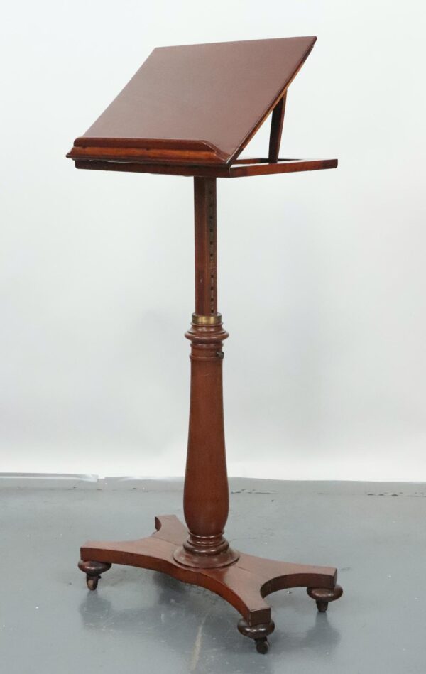 Antique walnut lectern stand with an adjustable slanted top, turned central post, and caster base, shown in a dark wood tone with a repaired crack on the reading surface.