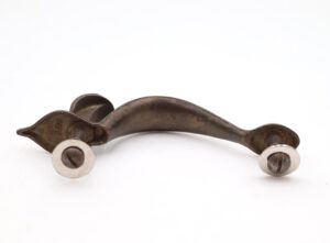 Vintage brass cabinet pull with a curved handle, two mounting posts, and visible screw heads.