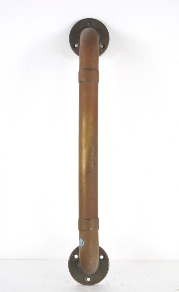 Vintage brass pipe door pull with round mounting plates shown vertically, featuring an antique patina and surface wear.