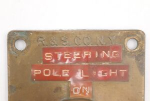 Antique brass ship light switch plate with two mounting holes, stamped R. & S. Co. NY and visible STEERING POLE LIGHT ON text.