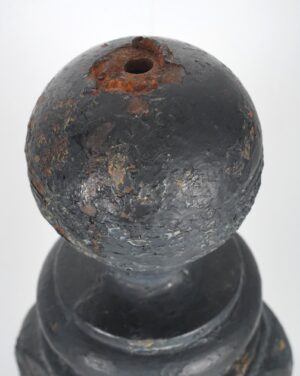 Close-up of a black cast iron newel post ball finial with chipped paint and rust spots.