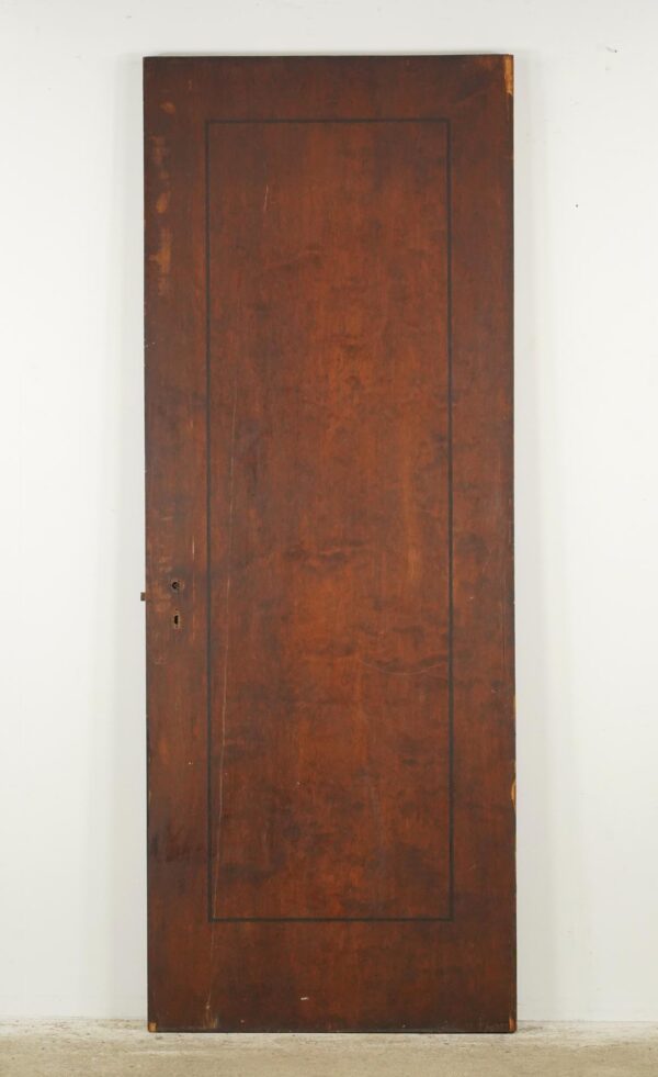 Vintage one-panel passage door in a dark wood tone, shown front on with surface wear, a keyhole, and attached original steel hardware.