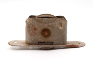 Antique steel window sash pulley with heavy surface wear and rust, shown front on with its mounting plate and pulley wheel visible.