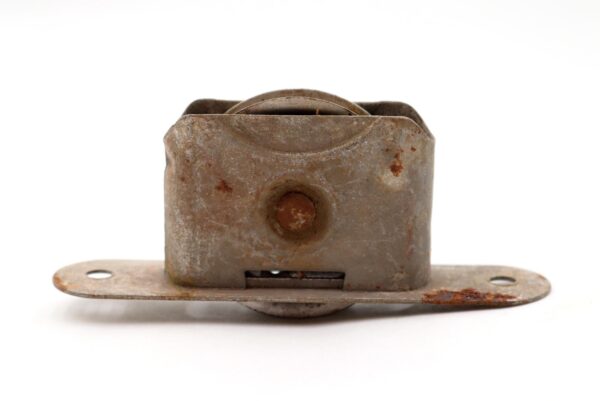 Antique steel window sash pulley with heavy surface wear and rust, shown front on with its mounting plate and pulley wheel visible.