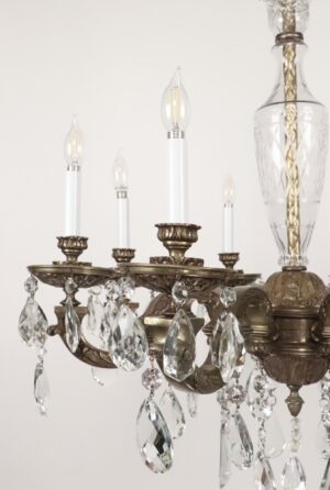 Close-up of a Victorian-style chandelier with an antique bronze frame, clear crystal pendants, and visible candle-style bulbs on ornate scrolling arms.
