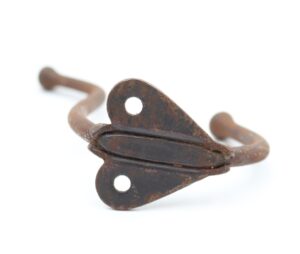 Vintage cast iron double arm wall hook with a rusted japanned finish and two mounting holes shown in close-up.