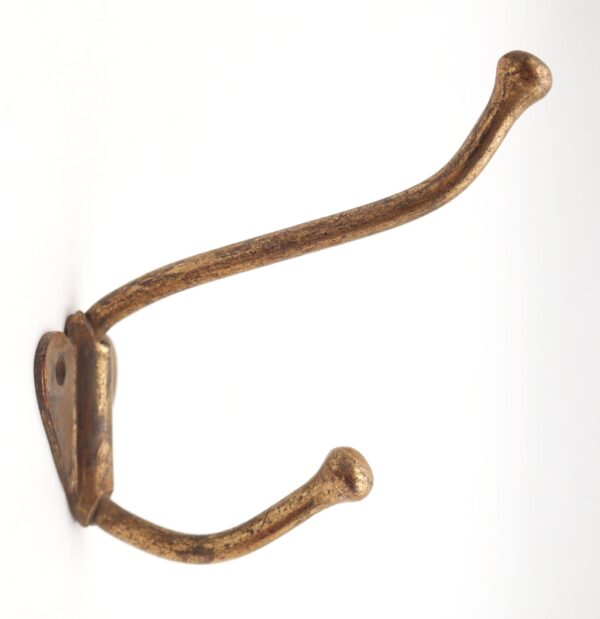 Vintage brass double arm wall hook with two curved arms and a single mounting plate, shown in close-up on a plain background.