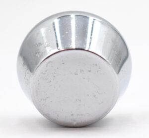 Close-up of a concave tulip cabinet knob with a chrome finish and visible surface wear.