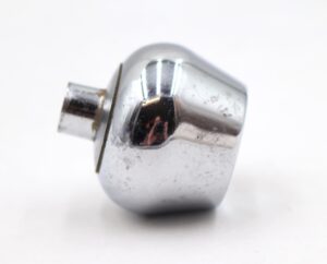 Chrome-finished brass cabinet knob with a concave tulip shape, shown in close-up from the side with visible surface wear.