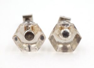 Pair of clear glass hexagon cabinet knobs shown front view, with bullet centers and mounting screws visible behind them.