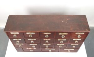 Top view showing all 18 drawers’ labels and round glass knobs arranged in neat rows on the cabinet.