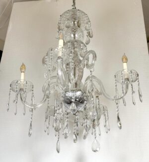 Five-arm crystal chandelier with candlestick lights and hanging pendants.
