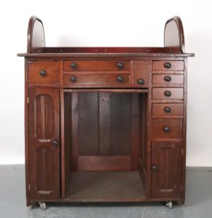 Front view highlighting small drawers, open central area, and curved sides with visible wear. Wheels peeking beneath base. Side angle showing one cupboard door slightly open, revealing shelves. Curved panel and wood grain visible. Close-up of drawer handles and aged finish, emphasizing texture and signs of use on the wood. Top-down perspective focusing on the cabinet’s surface and central open space between cupboards. Rear view displaying back panels, wheel casters, and frame construction details.