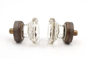 Pair of clear glass cabinet knobs with octagon-shaped faces and antique brass shanks shown side by side.