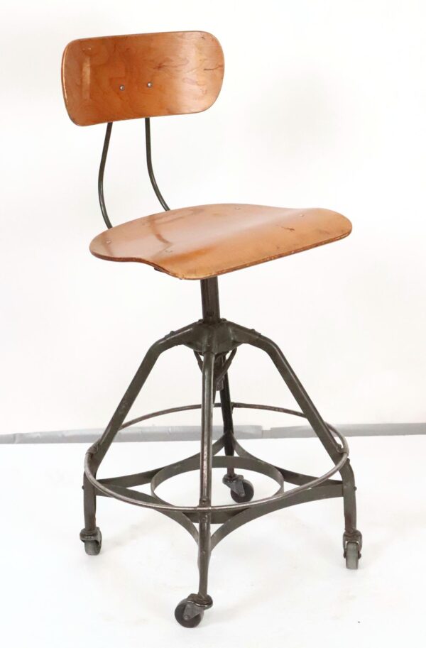 Front view of adjustable vintage industrial stool with wooden seat, backrest, metal frame, and four casters—ideal for studio use.