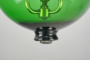 Close-up of a green bell jar pendant light with brass hardware and the lower socket assembly visible.
