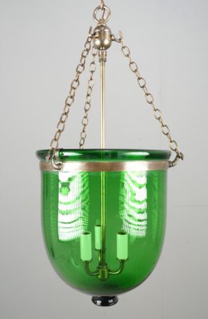 Green bell jar pendant light with antique brass hardware, shown front view with a hanging chain and three candle-style bulb sockets visible inside the curved shade.