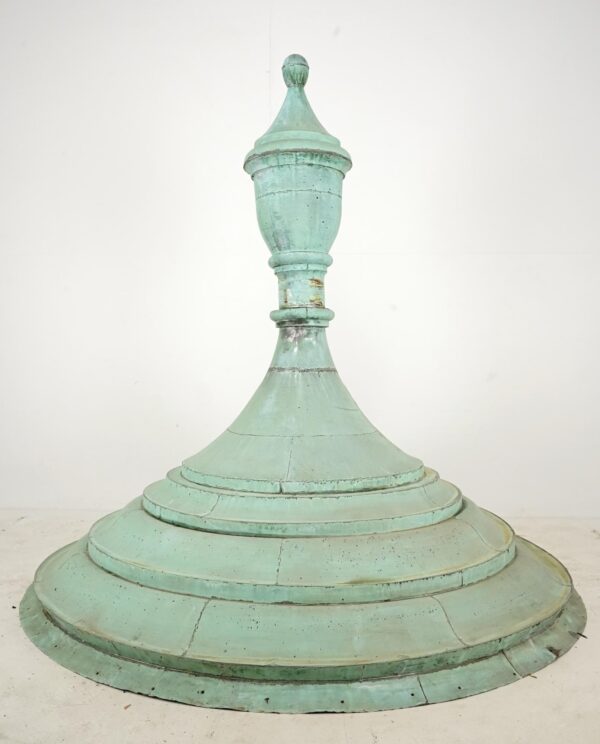 Multitiered copper rooftop finial with a verdigris finish, round base, and pointed ball top, shown with visible age wear and slight metal distortion.