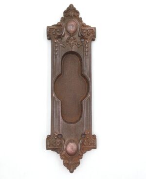 Victorian cast iron pocket door pull with an ornate recessed oval grip and mounting holes, shown front on.