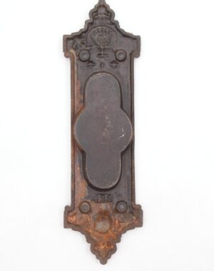 Victorian cast iron pocket door pull with an ornate recessed backplate, black finish, and visible rust and surface wear.