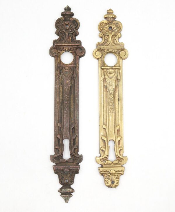 Pair of French-style bronze door back plates shown side by side, one with a dark antique brass finish and one with a lighter polished brass finish, each with an ornate keyhole opening and visible wear.