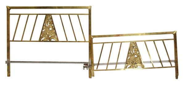 Art Deco brass headboard and footboard set with a geometric frame, centered bird and snake motif, and one intact foot.