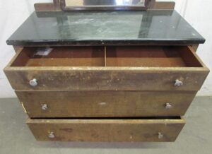 Vintage steel dresser with a framed mirror, showing three open drawers and a black top surface, with worn brown front panels and visible caster hardware at the corners.