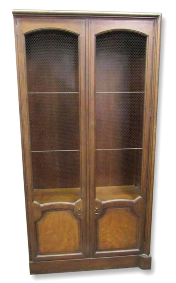French Provincial bookcase cabinet with wire mesh doors, shown front view with two arched doors and lower drawer panels in a dark wood tone.