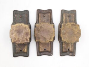 Three vintage drawer knobs with a hammered design and antique brass finish, shown with mounting holes and light surface wear.