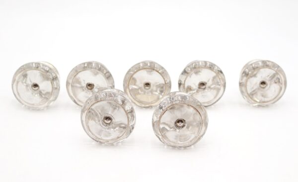 Set of seven clear round glass cabinet knobs with steel screws, shown front view with mounting holes visible.