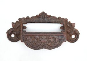 Victorian cast iron apothecary bin pull with a label slot and ornate scrollwork, shown front view with mounting holes on both ends.