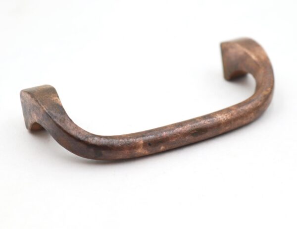 Curved brass cabinet pull with an antique finish and mounting holes visible at both ends.